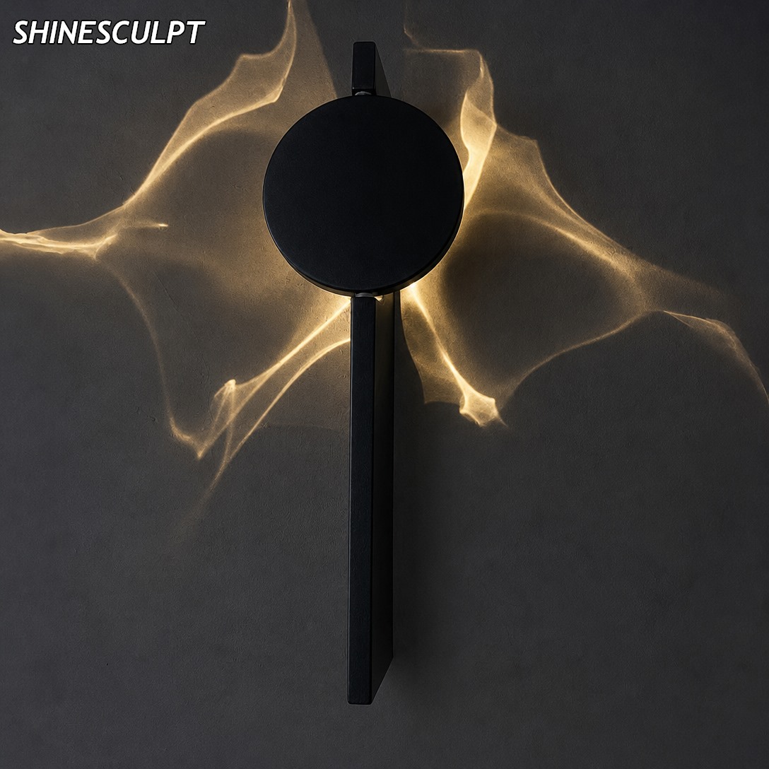 Stainless steel wall light switched on, warm petal light pattern on a charcoal wall